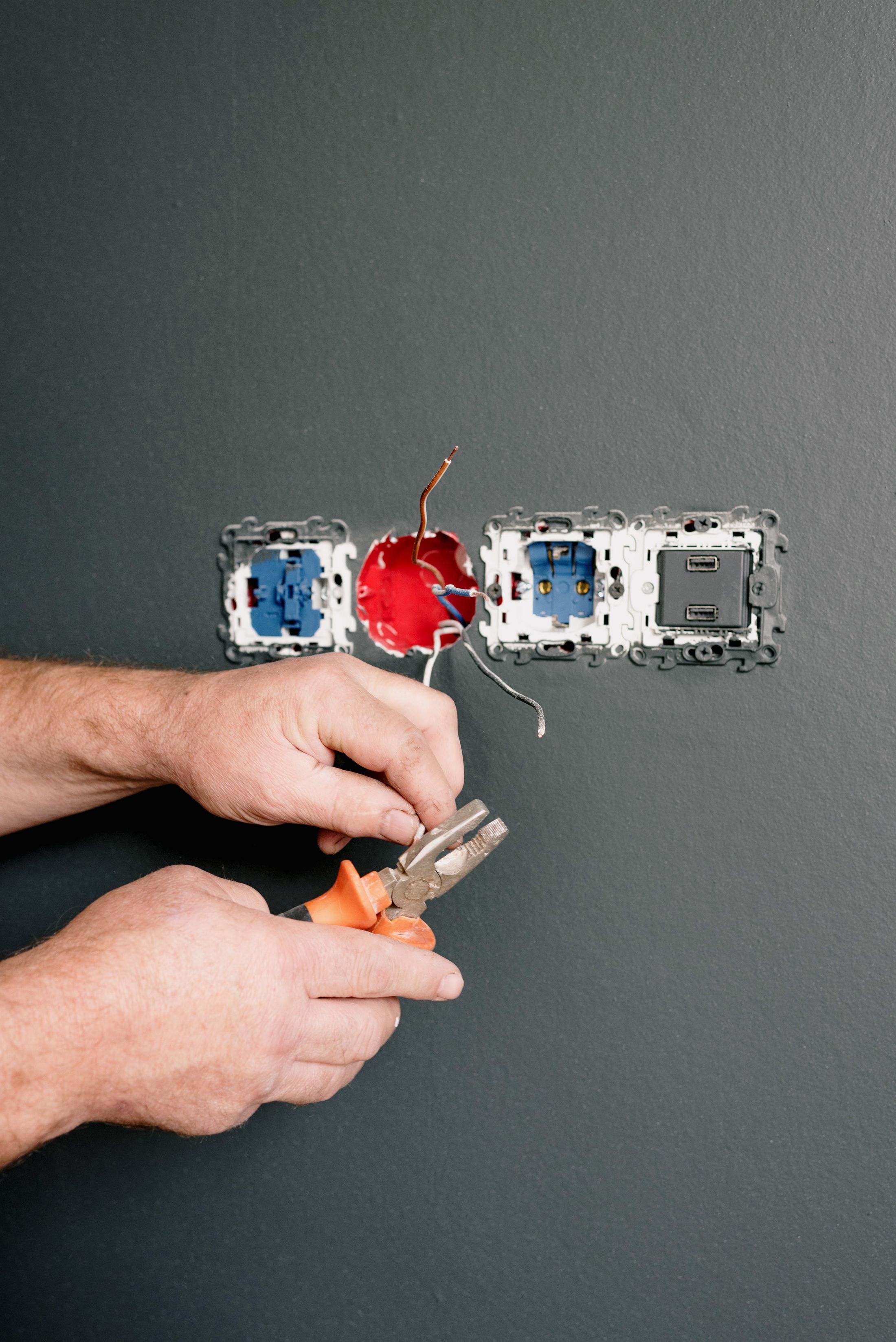 An electrician terminating cables into wall boxes during a rewire